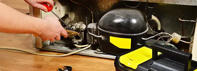 Refrigerator repair technician fixing the compressor and wiring in Glyndon, MN