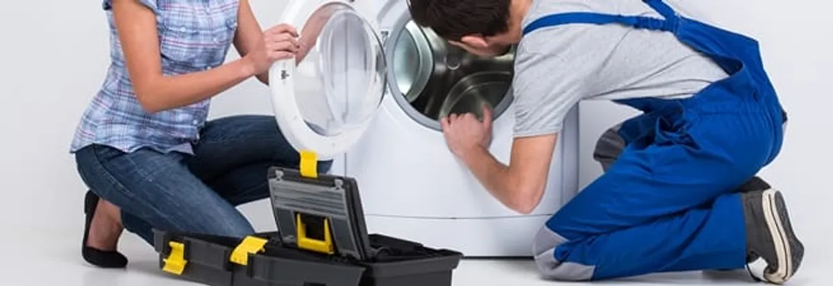 Washer repair technician inspecting a front-load washing machine with tools in Fargo, ND