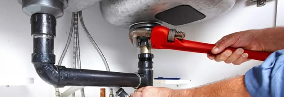 Garbage disposal repair technician tightening the sink drain and disposal connection in Fargo, ND