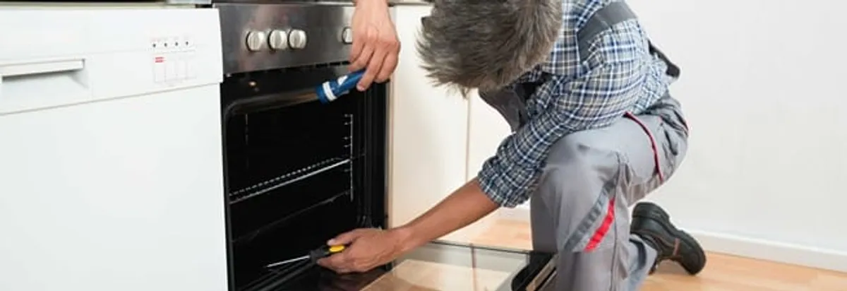 Oven repair technician inspecting and servicing an electric oven in Fargo, ND