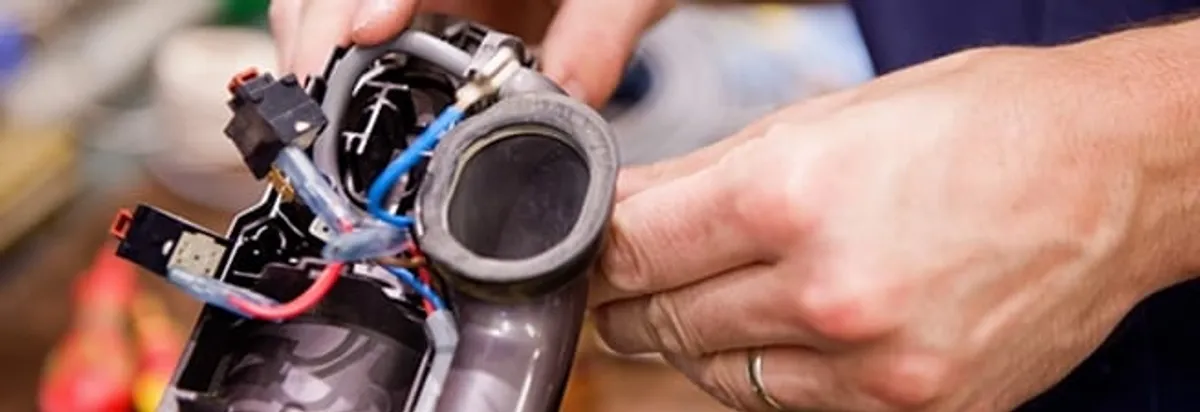 Vacuum repair technician reconnecting wiring and components in Fargo, ND
