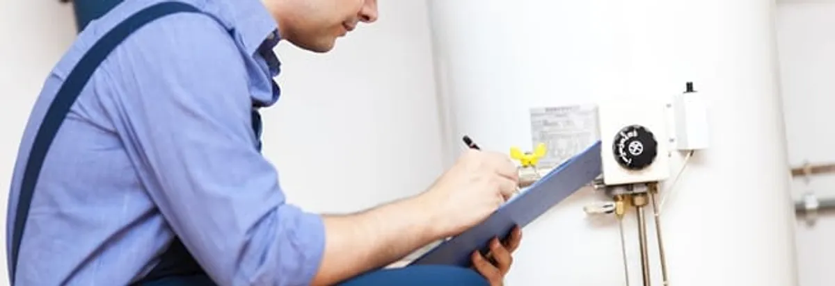 Water heater repair technician inspecting the unit and recording service notes in Fargo, ND