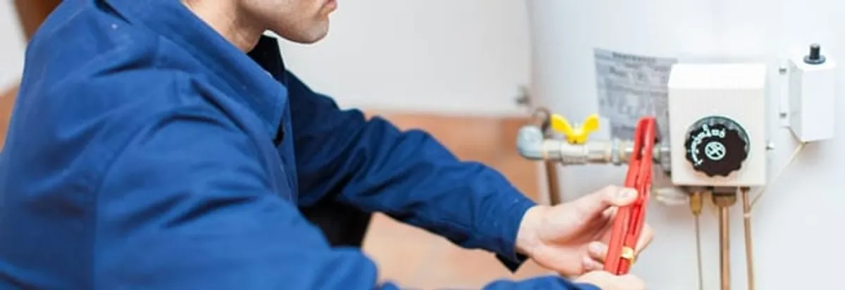 Water heater repair technician adjusting the temperature control and gas valve in Fargo, ND